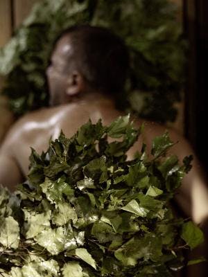 Mehrere Blätter und Kräuter liegen auf dem Rücken eines Mannes während einer Pirts Behandlung in der Tamina Therme.