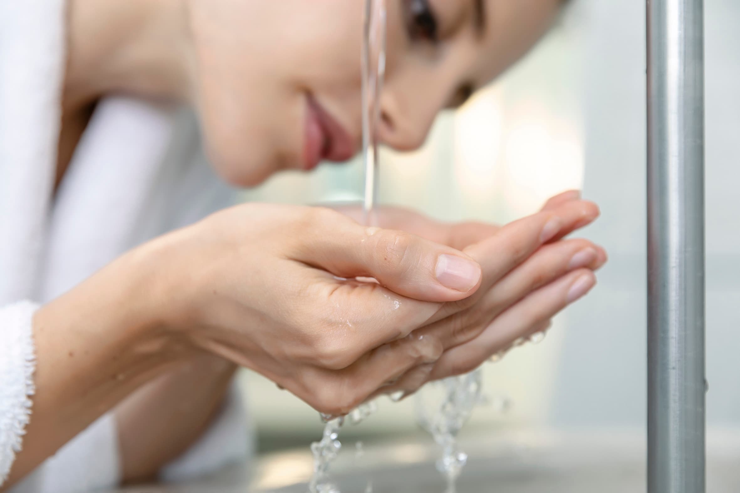 Nahaufnahme einer Frau, die von einem Trinkbrunnen trinkt.