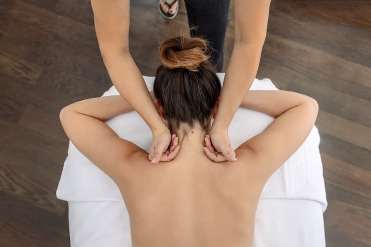 Eine Masseurin gibt einer Kundin eine Schultermassage in der Spa Welt der Tamina Therme.