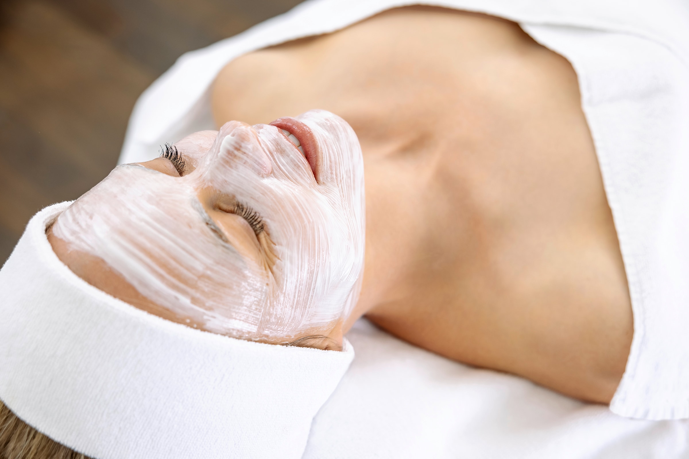 Eine Frau entspannt mit einer aufgetragenen Gesichtsmaske während der Apparativen Kosmetik.