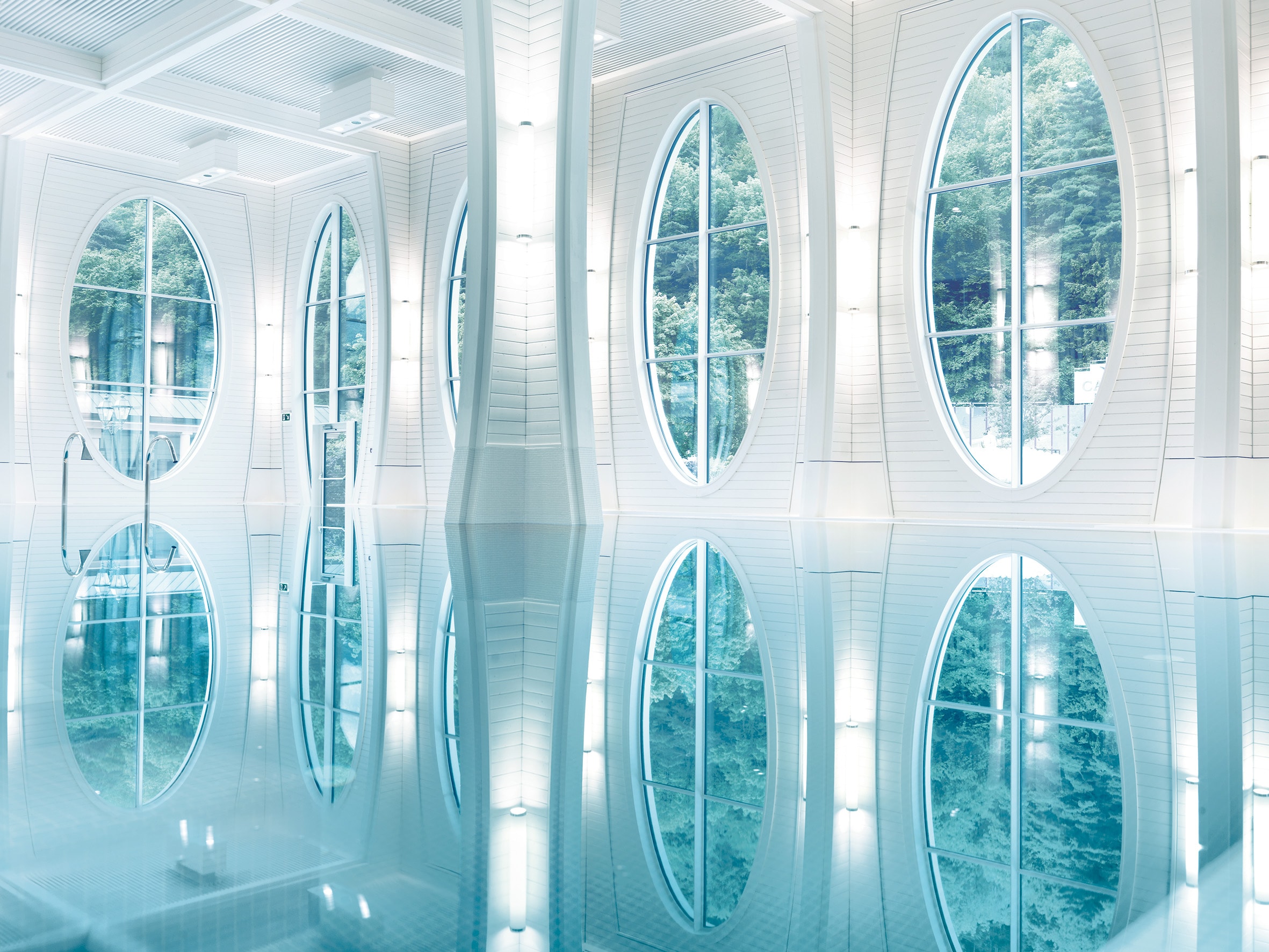 Das Thermalbad der Tamina Therme von Innen. Kristallklares Wasser, große Fenster und helle Wandfarben.