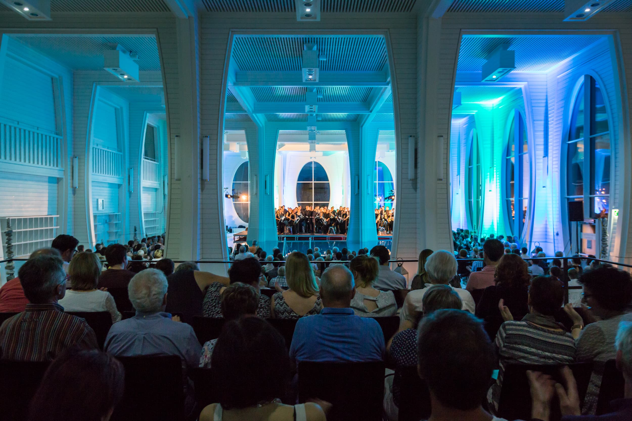 Mehrere Menschen sitzen auf Stühlen und lauschen einem Konzert in der Tamina Therme.