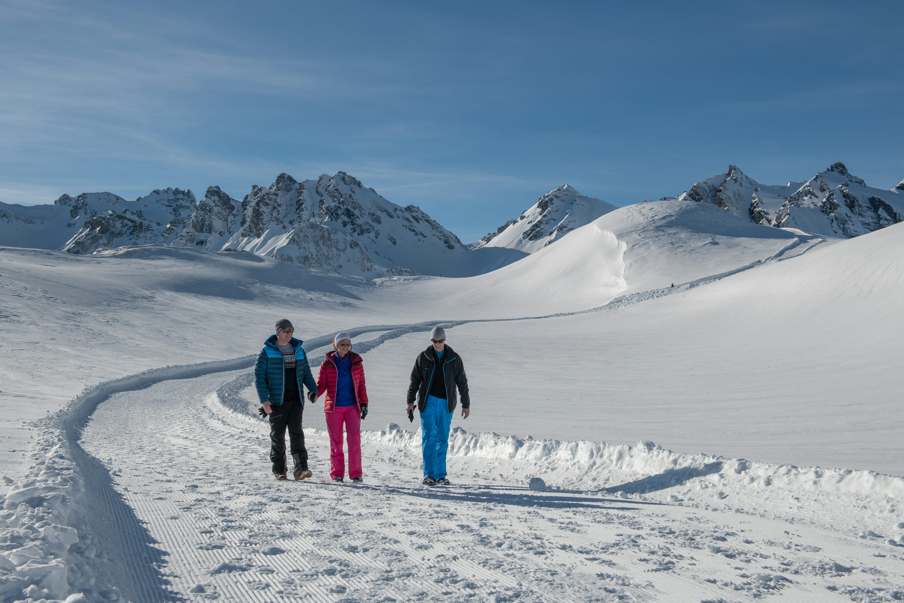 Drei Personen wandern durch eine verschneite Landschaft am Pizol.