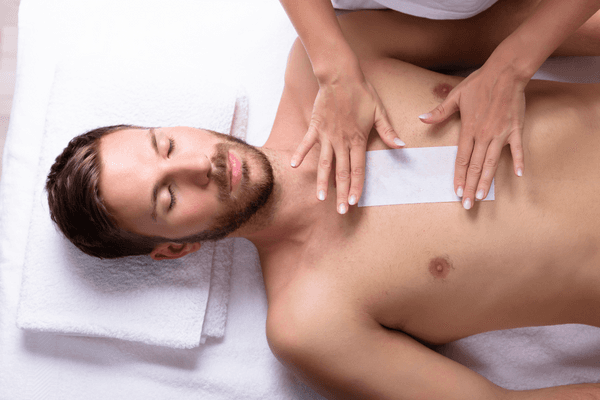 Einem Mann werden die Brusthaare durch ein Waxing entfernt.