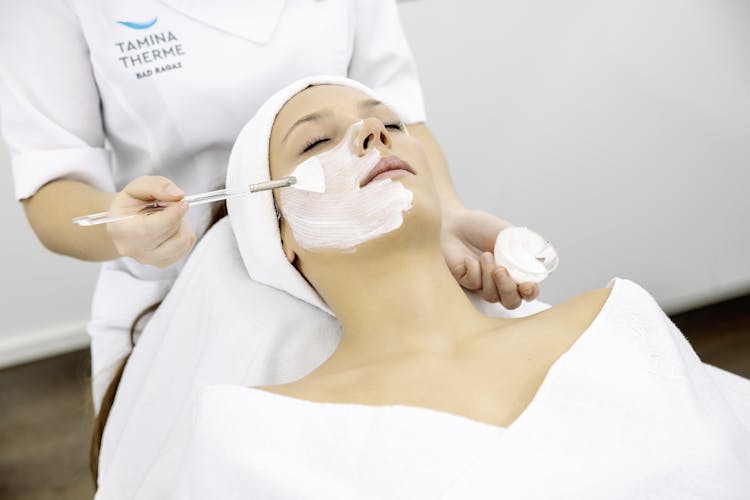 Eine Kosmetikerin trägt eine Gesichtsmaske bei einer Kundin der Tamina Therme auf.