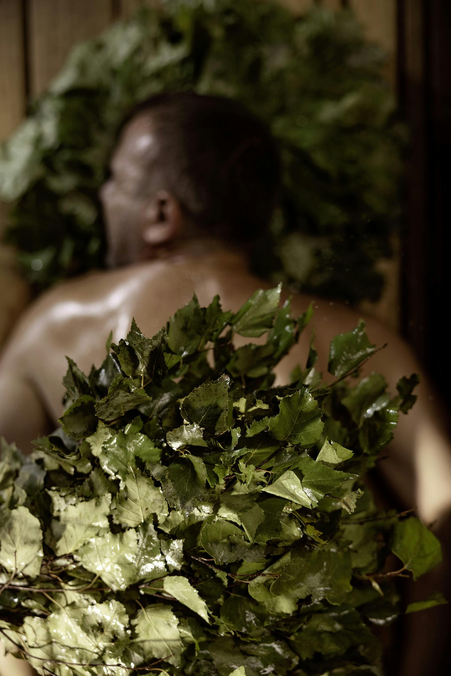 Mehrere Blätter und Kräuter liegen auf dem Rücken eines Mannes während einer Pirts Behandlung in der Tamina Therme.