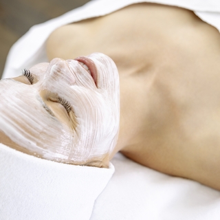 Eine Frau entspannt mit einer aufgetragenen Gesichtsmaske während der Apparativen Kosmetik.