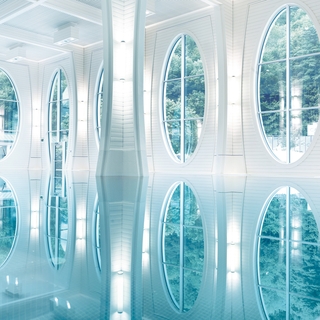 Das Thermalbad der Tamina Therme von Innen. Kristallklares Wasser, große Fenster und helle Wandfarben.