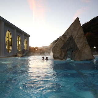Zwei Personen schwimmen im Außenpool der Tamina Therme in der Schweiz.