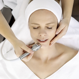 Eine Frau bekommt eine Behandlung mit Ultraschall im Gesicht.