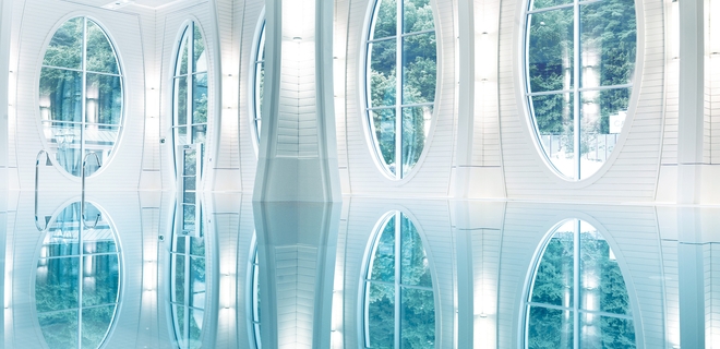 Das Thermalbad der Tamina Therme von Innen. Kristallklares Wasser, große Fenster und helle Wandfarben.