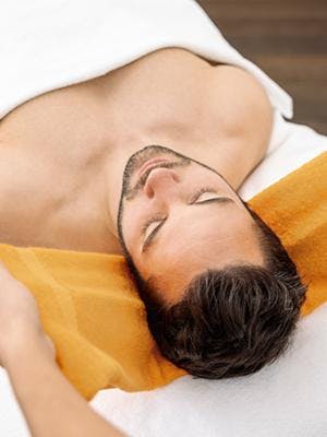 Ein Mann liegt mit seinem Kopf in einem Handtuch und entspannt während der haki Behandlung in der Tamina Therme.